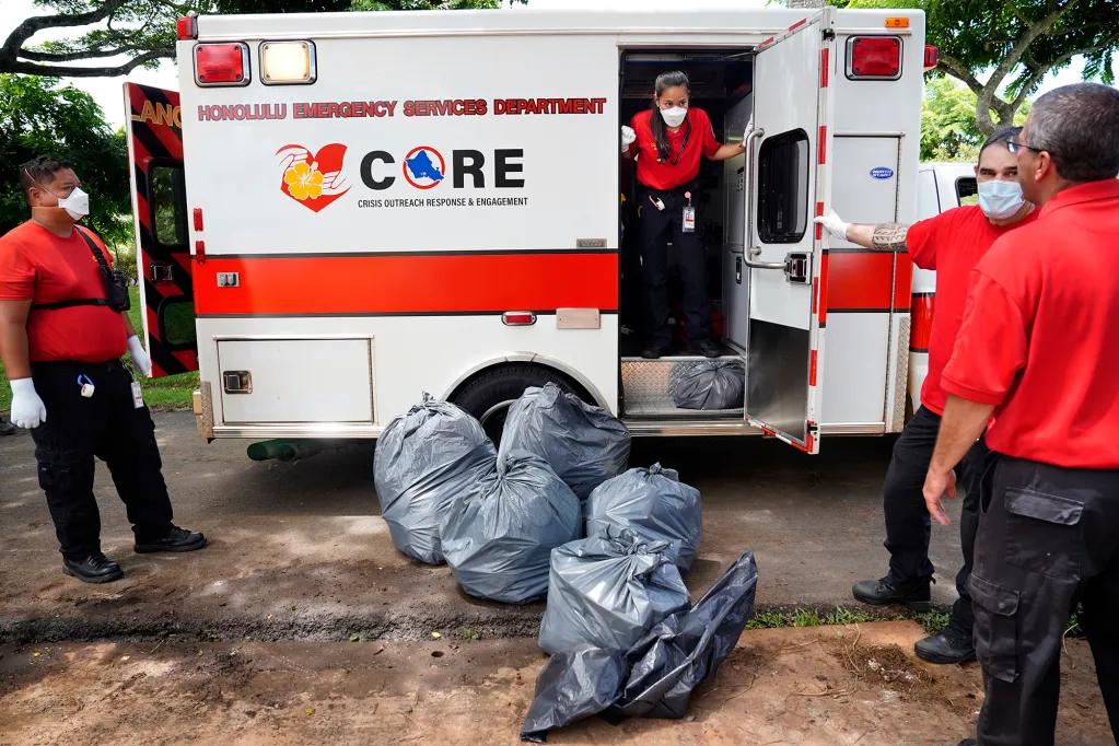 Honolulu CORE team EMT Bethany Nakano in the ambulance, talks with EMS director Jim Ireland, far right, after picking up a homeless patient outside Adventist Health Castle hospital. (Kevin Fujii/Civil Beat/2024)