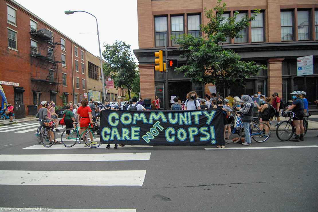 Protesters hold a banner calling for investment in communities, not the police