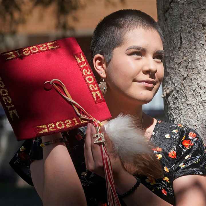 Emalyce Kee, holding up her "forbidden" graduation cap that she decorated with Native beads on May 25, 2022, in Cedar City, Utah.